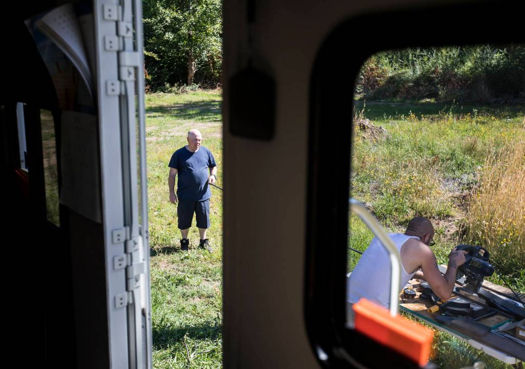 Benjamin Stum holds a piece of trim steady while his brother, Joshua Standridge, cuts it to measurement. (Olivia Vanni / The Herald)