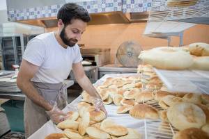 Nechirvan Zebari sorts through freshly made pita bread at Alida's Bakery on Friday, June 25, 2021 in Everett, Wa. (Olivia Vanni / The Herald)
