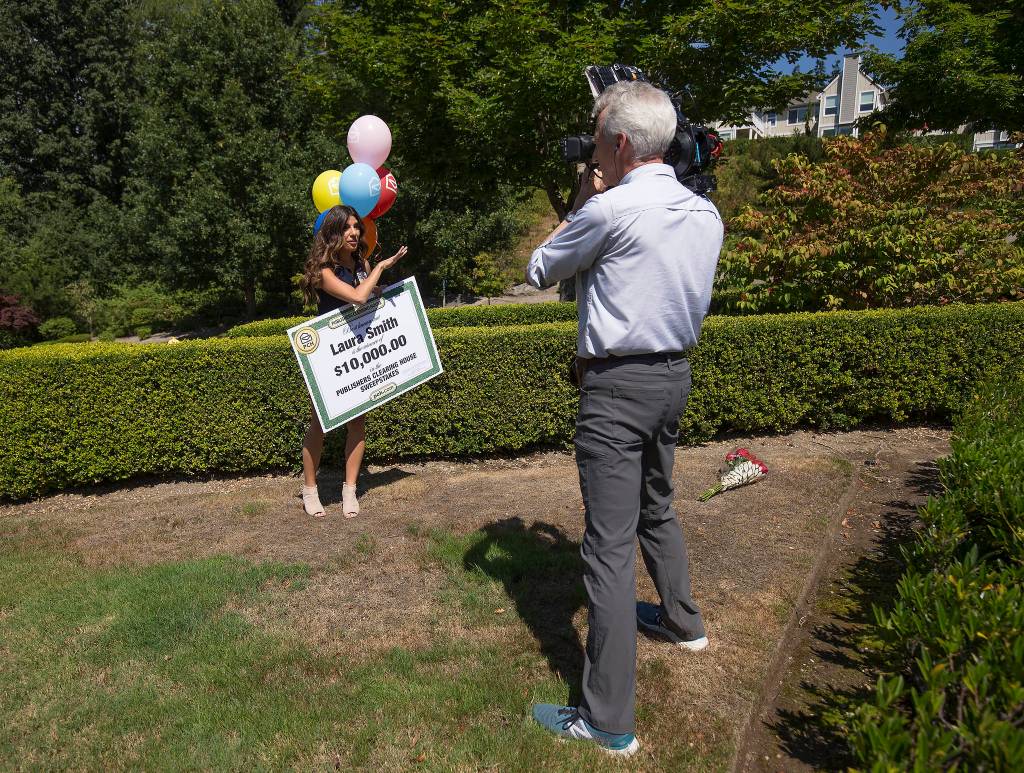 As Geoff Dunlap records, Danielle Lam, aka The Prize Patrol from Publishers Clearing House, tapes a introduction before delivering a check to the winner July 28 in Mukilteo. (Andy Bronson / The Herald)