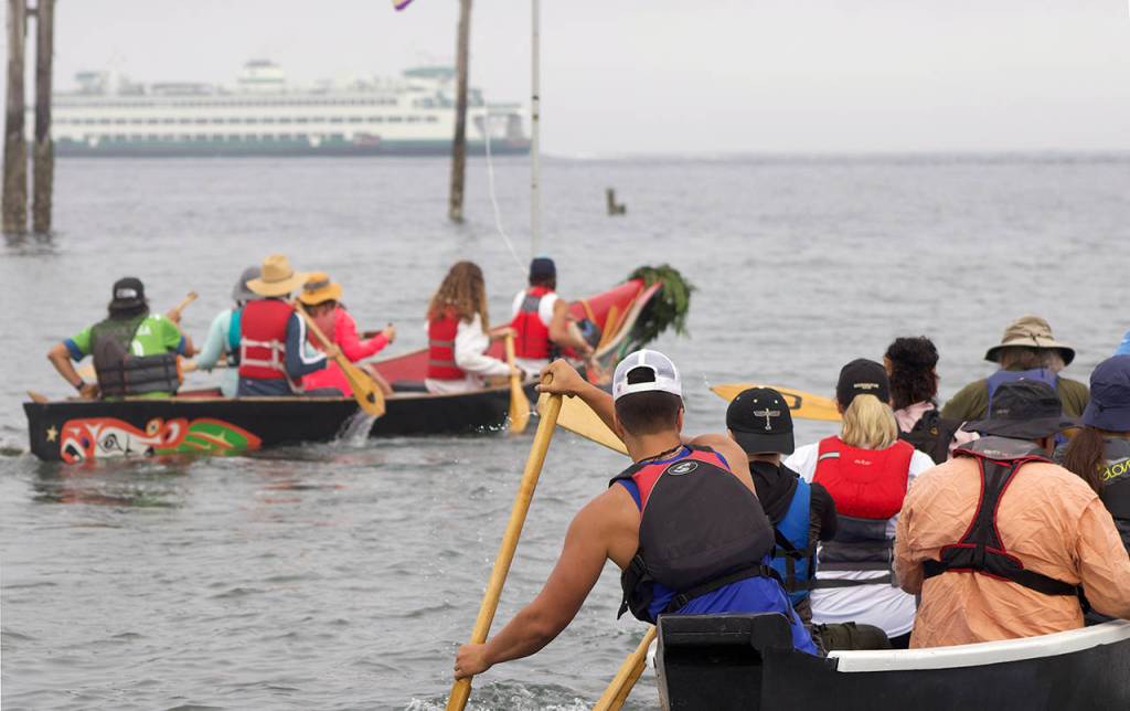 Members of the Blue Heron Canoe Family paddle away from the Edmonds waterfront to begin their two week journey to Lummi Island. (Isabella Breda / The Herald)