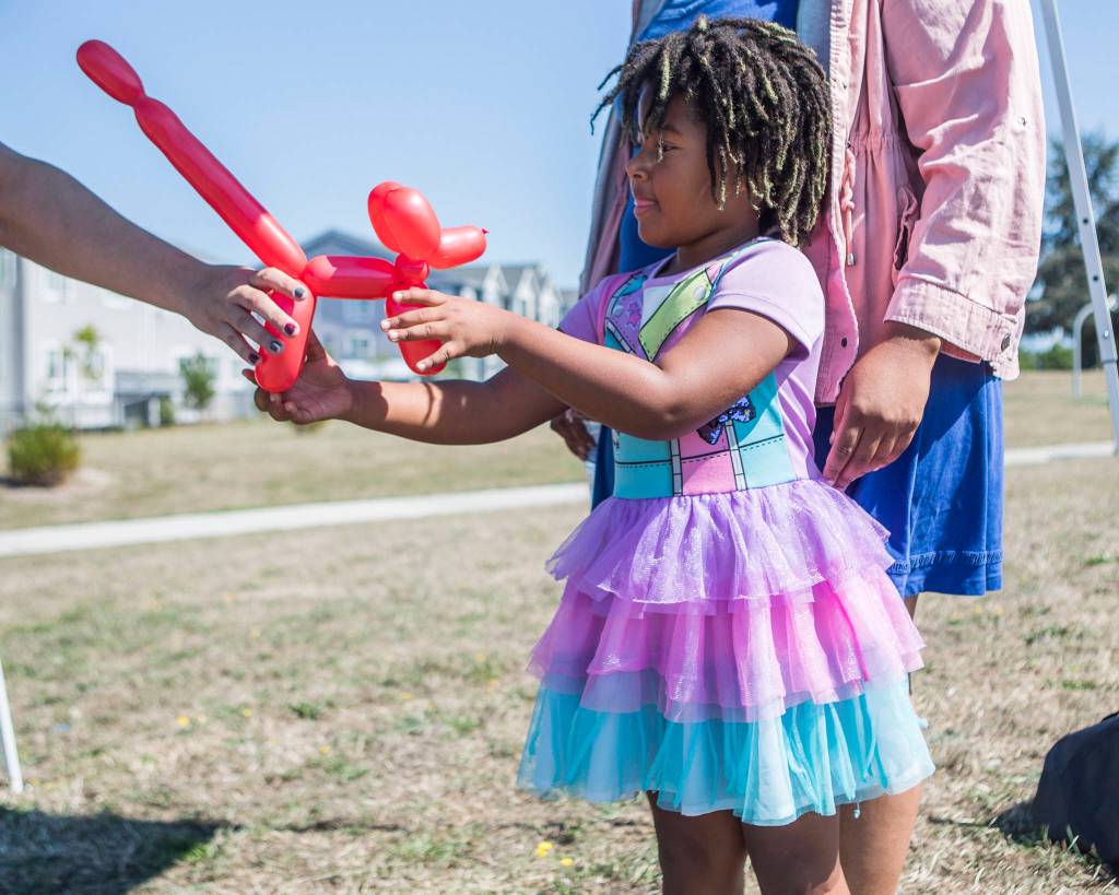 Maylani Moore receives a red balloon dog from ballon artist Sara Lynn at the Delta Art Experience at Henry M. Jackson Park in Everett. (Olivia Vanni / The Herald)
