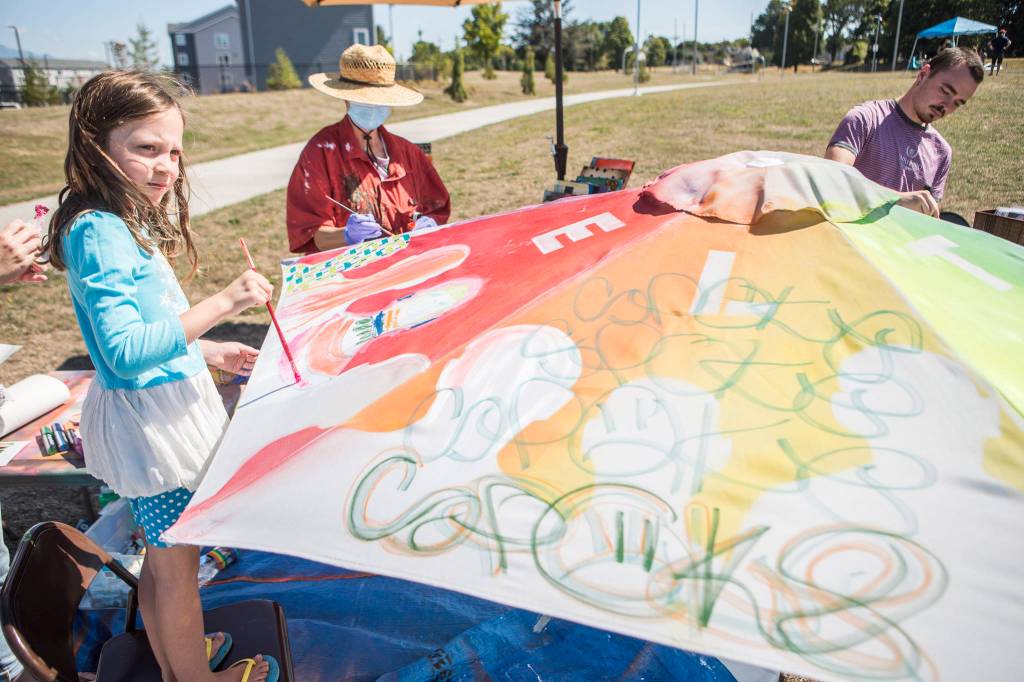 People add their touches to a painted umbrella at the Delta Art Experience at Henry M. Jackson Park in Everett. (Olivia Vanni / The Herald)
