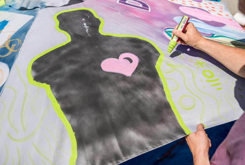 The silhouette of a persons torso adorns the top of an umbrella as others decorate it Sunday in Everett. (Olivia Vanni / The Herald)