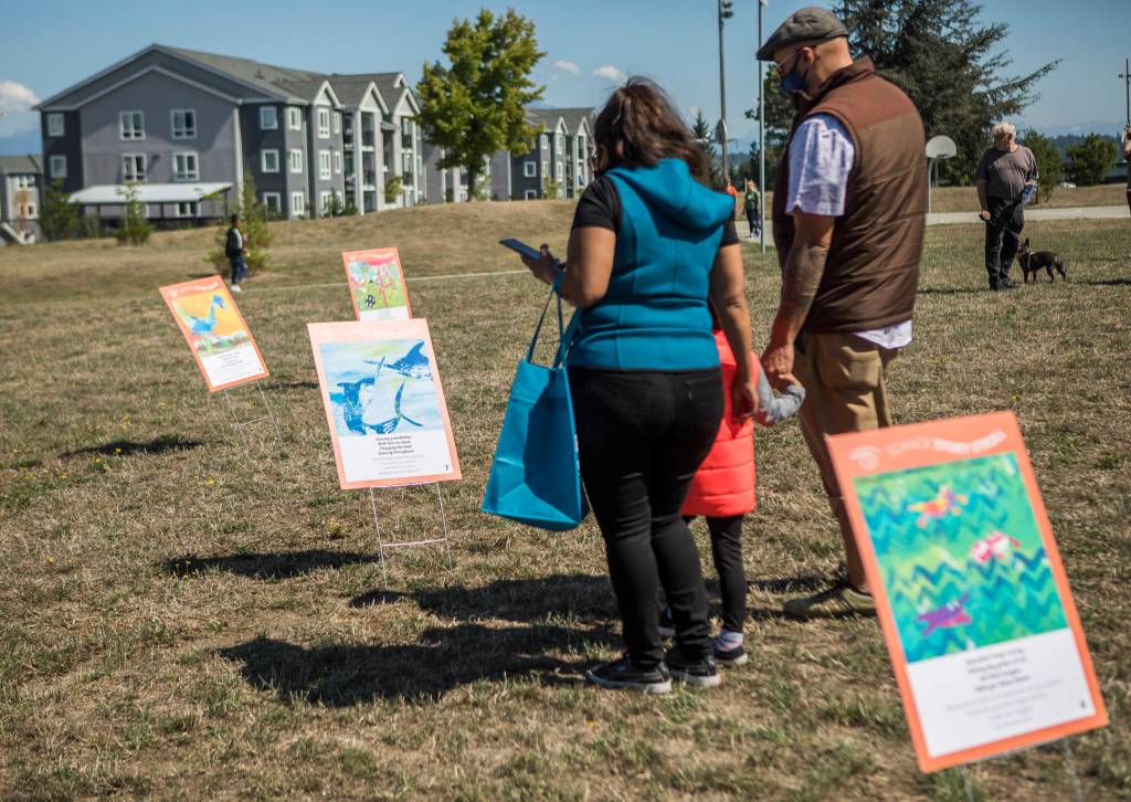 People examine the art walk information Sunday during the Delta Art Experience in Everett. (Olivia Vanni / The Herald)