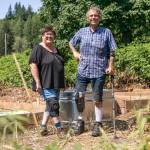 Arleen Gibson and Mike Dailey stand in the overgrown veteran garden at Hope Horses N Healing, owned by Gibson, in Monroe. (Hannah Sheil / The Herald)
