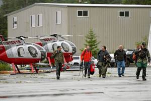 Ketchikan Volunteer Rescue Squad personnel land and disembark from a Hughes 369D helicopter on Thursday, Aug. 5, 2021, at Temsco Helicopters Inc in Ketchikan, Alaska. The KVRS, U.S. Coast Guard, Alaska State Troopers and U.S. Forest Service responded to a radio beacon alert from a downed Southeast Aviation de Havilland Beaver float plane that was carrying five passengers from the Holland America Line cruise ship Nieuw Amsterdam, according to Coast Guard, Holland America and KVRS information. The sightseeing plane crashed Thursday in southeast Alaska, killing all six people on board, the U.S. Coast Guard said.  (Dustin Safranek/Ketchikan Daily News via AP)