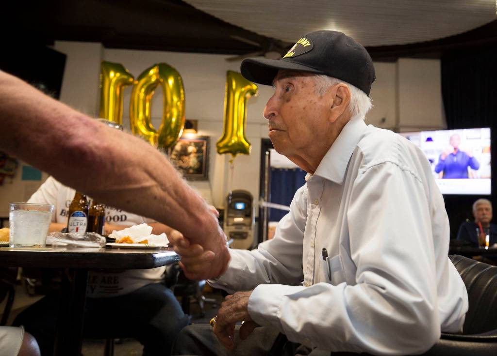 Veteran Larry Negrette, 101, gets a handshake from a fellow service member as the Everett VFW Post hosted a birthday party for him on Tuesday in Everett. (Andy Bronson / The Herald)