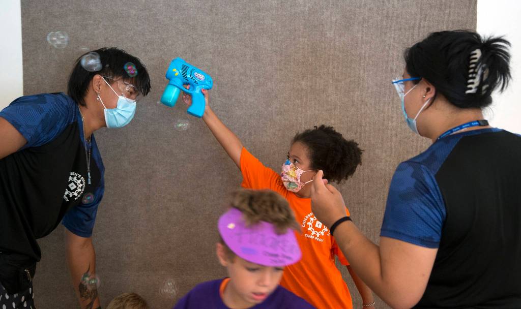 Ellison Lombard tries to get soap bubbles to land on Sage Oliverias head during craft time of Camp Prov in Everett. (Andy Bronson / The Herald)