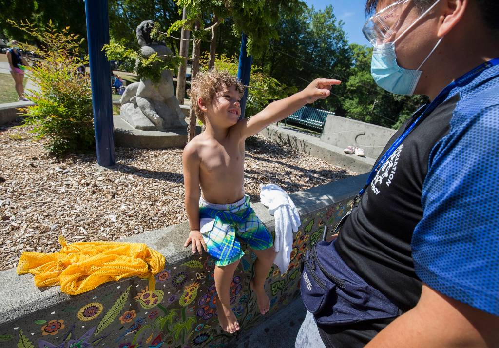 Soren Williams, 4, points at Quang Pham and says, I love you, after drying off from playing in the water at Forest Park in Everett. (Andy Bronson / The Herald)