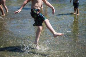 A child kicks water in a large puddle at Walter E. Hall Park on Saturday, June 26, 2021 in Everett, Wa. (Olivia Vanni / The Herald)