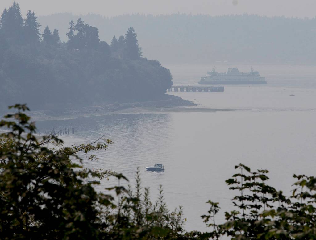 Engulfed in smoke, a ferry pulls away from the Mukilteo terminal and boats navigate the water in front of Everetts Howarth Park on Friday. (Olivia Vanni / The Herald)