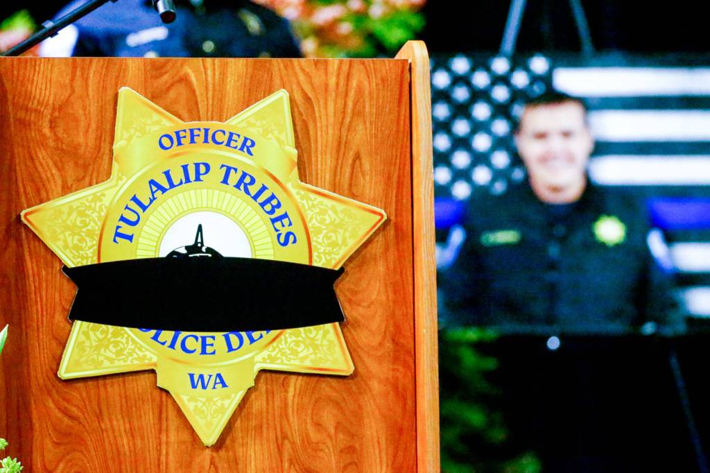 A black band adorns a Tulalip Tribes Police Department badge at the memorial service for Officer Charlie Joe Cortez on Tuesday at Angel of the Winds Arena in Everett. (Kevin Clark / The Herald)