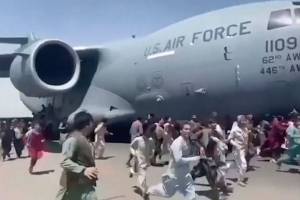 Some hundreds of people run alongside a U.S. Air Force C-17 transport plane as it moves down a runway of the international airport, in Kabul, Afghanistan, Monday, Aug. 16. 2021. Thousands of Afghans have rushed onto the tarmac of Kabul’s international airport, some so desperate to escape the Taliban capture of their country that they held onto an American military jet as it took off and fell to their death. (Verified UGC via AP)