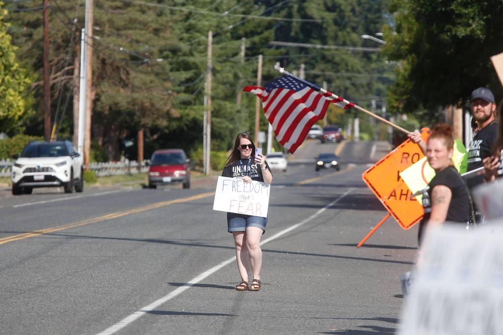 Protesters gather in front of the Marysville School District office on Wednesday to voice their anger over mask mandates in schools. (Andy Bronson / The Herald)