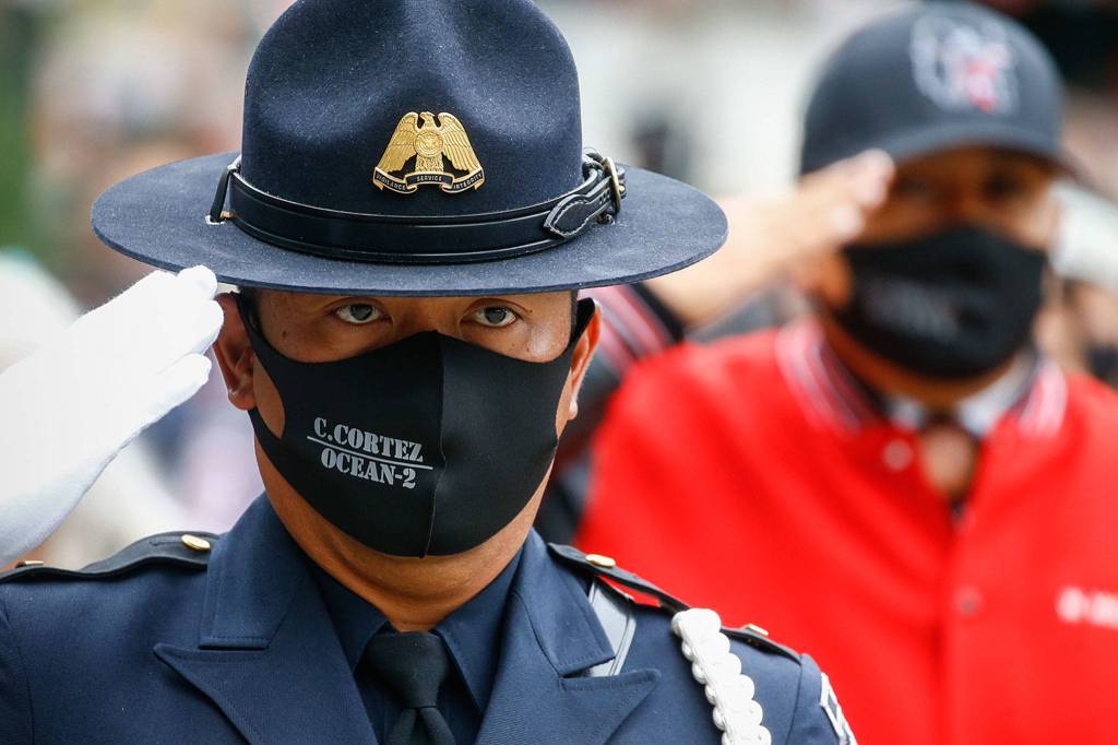 A officer salutes the symbolic remains of Officer Charlie Joe Cortez Tuesday afternoon at the Angel of the Winds Arena in Everett on August 17, 2021.  (Kevin Clark / The Herald)