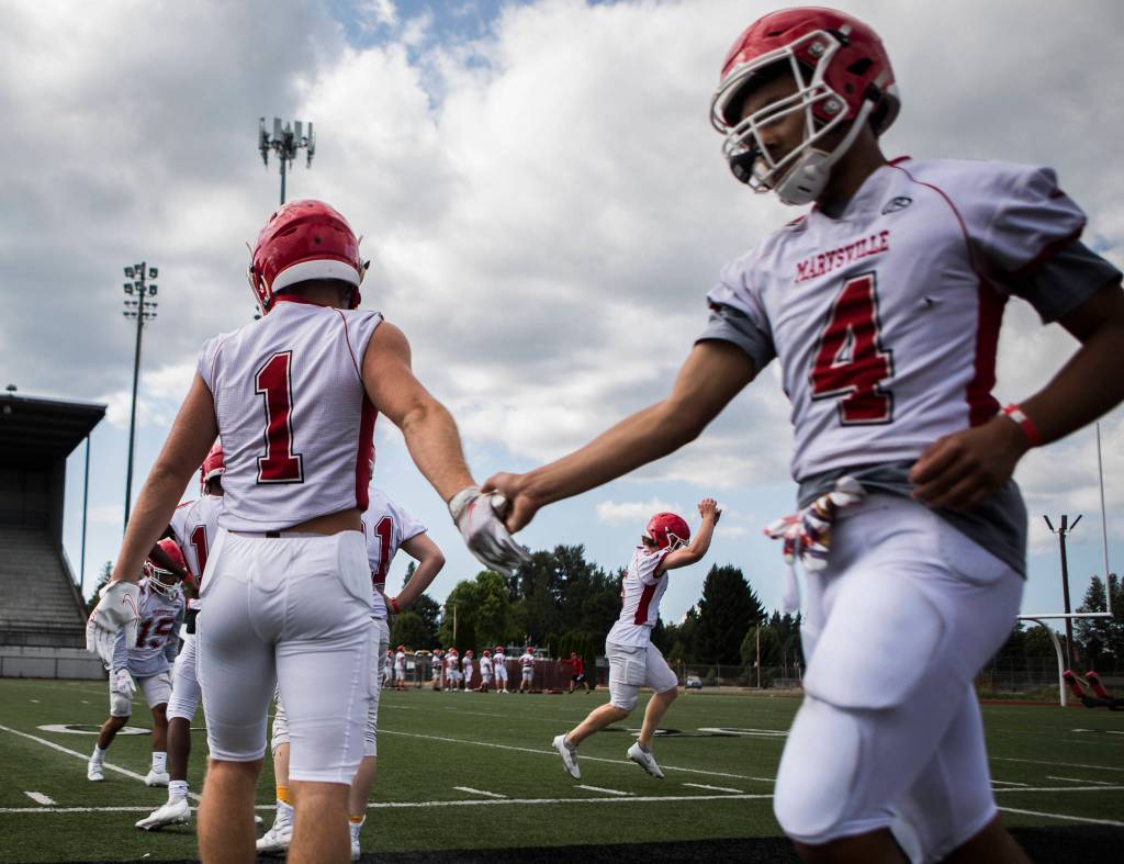 Marysville Pilchucks Miguel Chavez (left) high-fives Samtuala Gray during football practice on Thursday in Marysville. (Olivia Vanni / The Herald)