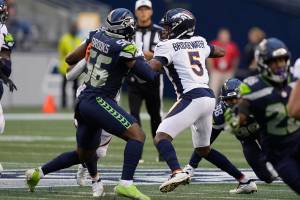 Denver Broncos quarterback Teddy Bridgewater (5) looks for a receiver while under pressure from Seattle Seahawks linebacker Jordyn Brooks (56) during the first half of an NFL preseason football game Saturday, Aug. 21, 2021, in Seattle. (AP Photo/Stephen Brashear)