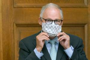 Washington Gov. Jay Inslee puts on a mask after speaking at a news conference, Wednesday, Aug. 18, 2021, at the Capitol in Olympia, Wash. Inslee announced that Washington state is expanding its vaccine mandate to include all public, charter and private school teachers and staff, as well as those working at the state's colleges and universities. The governor also expanded the statewide indoor mask mandate in place for non-vaccinated individuals to include those who are vaccinated. (AP Photo/Ted S. Warren)
