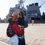 Chief Anthony Strowder kisses his wife, Anika, while holding his children, Idris and Naiem, after walking off the USS John Paul Jones. The Arleigh Burke-class guided missile destroyer docked at Naval Station Everett on Monday and will be homeported there. (Andy Bronson / The Herald)