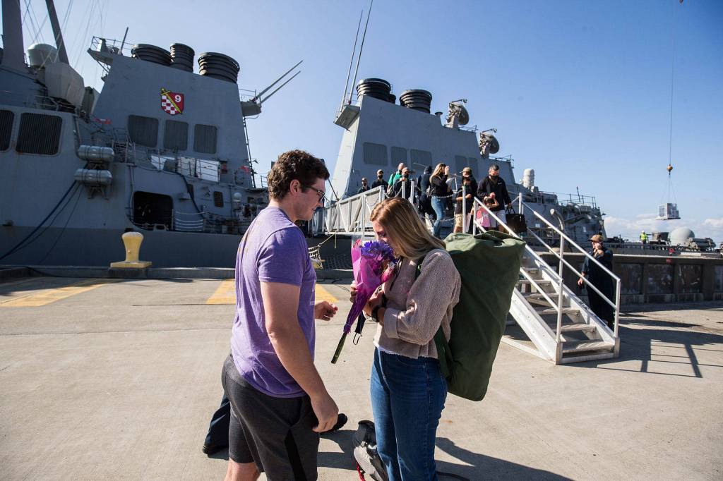 Ensign Rennie Scott (right) smells flowers brought by Aaron Crockett as she and sailors of the USS John Paul Jones disembark at Naval Station Everett on Monday. (Andy Bronson / The Herald)
