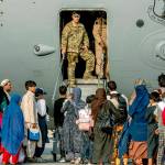 U.S. Air Force service members prepare to board evacuees from Afghanistan onto a C-17 Globemaster lll on Sunday at Al Udeid Air Base, Qatar. (Airman 1st Class Kylie Barrow/U.S. Air Force via AP)