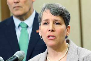 FILE - In this Jan. 24, 2019 file photo Washington Gov. Jay Inslee, left, looks on as Suzi LeVine, right, the state's Employment Security Department Commissioner, talks to reporters at the Capitol in Olympia, Wash. The state of Washington is calling in the National Guard to help process unemployment benefit claims as officials grapple with a backlog caused in part by a fraud ring that stole more than half a billion dollars in aid, officials said Thursday, June 11, 2020. LeVine said that Gov. Jay Inslee approved the deployment of troops who will start assisting her team next week as it tries to reduce the unemployment claim backlog.(AP Photo/Ted S. Warren,File)