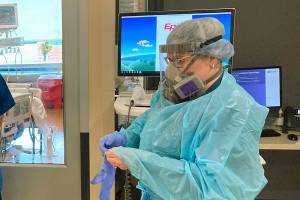 FILE - In this Aug. 20, 2021, file photo, two visitors peer into the room of a COVID-19 patient in the intensive care unit at Salem Hospital in Salem, Ore., as a nurse dons full protective gear before going into the room of another patient. Gov. Kate Brown announced Wednesday, Aug. 25, 2021, that the state has contracted with a medical staffing company to provide up to 500 health care workers to hospitals around the state to help respond to the surge in patients due to the delta variant. (AP Photo/Andrew Selsky, File)