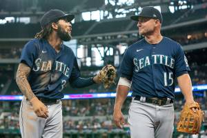 Seattle Mariners shortstop J.P. Crawford (3) jokes with third baseman Kyle Seager (15) during a baseball game against the Texas Rangers Thursday, Aug. 19, 2021, in Arlington, Texas. Seattle won 9-8 in 11 innings. (AP Photo/Jeffrey McWhorter)