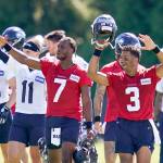 Seattle Seahawks quarterbacks Russell Wilson (3) and Geno Smith (7) lead teammates to wave at fans after NFL football practice in Renton, Wash., Wednesday, Aug. 11, 2021. (AP Photo/Elaine Thompson)