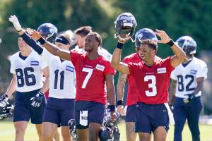 Seattle Seahawks quarterbacks Russell Wilson (3) and Geno Smith (7) lead teammates to wave at fans after NFL football practice in Renton, Wash., Wednesday, Aug. 11, 2021. (AP Photo/Elaine Thompson)