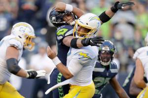 Los Angeles Chargers quarterback Chase Daniel, front right, is hit by Seattle Seahawks linebacker Cody Barton, causing a fumble that was recovered by the Seahawks for a touchdown during the first half of an NFL football preseason game Saturday, Aug. 28, 2021, in Seattle. (AP Photo/John Froschauer)