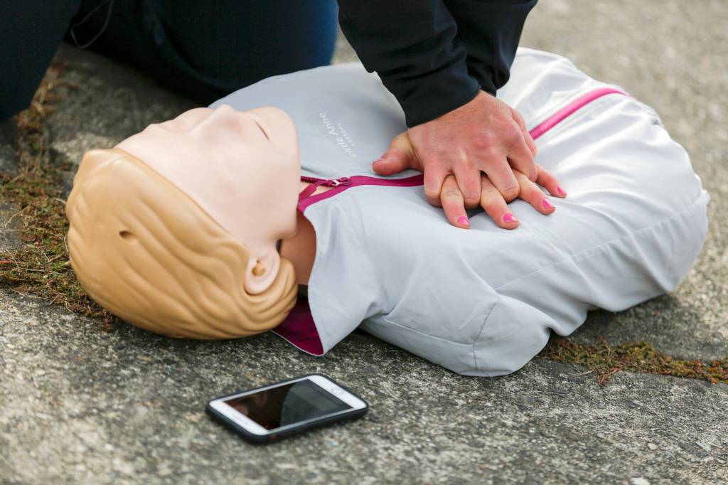 Capt. Kate Songhurst keeps time with the PulsePoint app during a CPR demonstration Tuesday at Kasch Park in Everett. (Kevin Clark / The Herald)