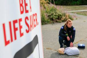 Capt. Kate Songhurst demonstrates proper CPR during the PulsePoint launch press briefing Tuesday morning at Kasch Park in Everett on September 14, 2021. (Kevin Clark / The Herald)