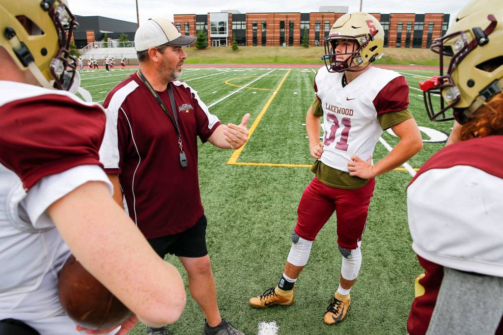 Dan Teeter, head coach, talks with Justice Taylor during a quarterback huddle in practice Tuesday afternoon at Lakewood High School in Arlington. (Kevin Clark / The Herald)