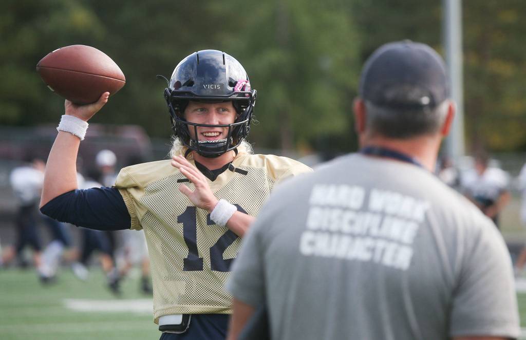 Arlington senior quarterback Trent Nobach talks with head coach Greg Dailer during practice on Tuesday, Aug. 31, 2021 in Arlington, Washington. Nobach, one of the top quarterbacks in the state, is back from injury after suffering a broken collarbone in the first game of this past spring's season. (Andy Bronson / The Herald)