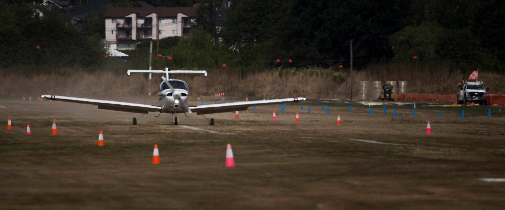 A plane lands on the grass runway at Harvey Field in Snohomish as work starts on the nearby asphalt runway. (Andy Bronson / The Herald)