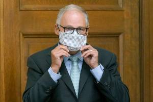 Washington Gov. Jay Inslee puts on a mask after speaking at a news conference, Wednesday, Aug. 18, 2021, at the Capitol in Olympia, Wash. Inslee announced that Washington state is expanding its vaccine mandate to include all public, charter and private school teachers and staff, as well as those working at the state's colleges and universities. The governor also expanded the statewide indoor mask mandate in place for non-vaccinated individuals to include those who are vaccinated. (AP Photo/Ted S. Warren)