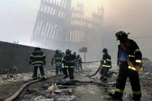 Firefighters work beneath the destroyed mullions, the vertical struts, of the World Trade Center in New York on Tuesday, Sept. 11, 2001. (AP Photo/Mark Lennihan)