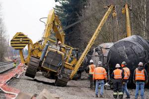 A piece of heavy equipment goes up onto one track while working to move one of several train cars which had been hauling crude oil and derailed a week earlier, Tuesday, Dec. 29, 2020, in Custer, Wash. The cause of the derailment of the oil cars Dec. 22 in Whatcom County is still unknown. A spokesperson for BNSF Railways said three cars ruptured, spilling an unknown amount of crude oil onto the ground. (AP Photo/Elaine Thompson)