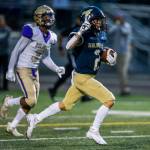 Arlingtons Levi Younger holds up two fingers as he runs the ball into the end zone for his second touchdown of the night during a game against Oak Harbor on Friday in Arlington. (Olivia Vanni / The Herald)