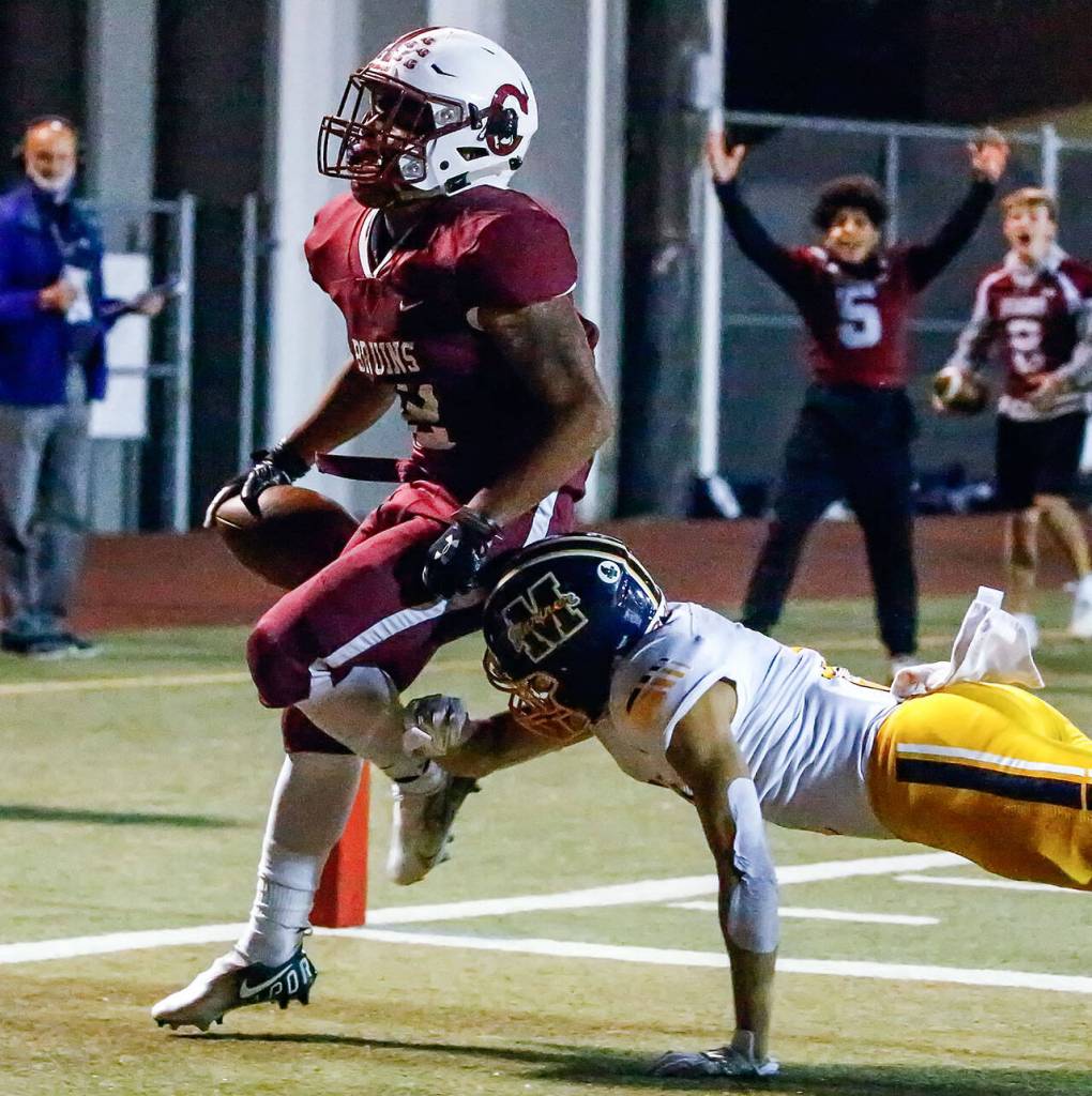 Cascades Julian Thomas crosses the goal line for a touchdown with Mariners Isaiah Cuellar trailing in the first quarter Friday evening at Everett Memorial Stadium. (Kevin Clark / The Herald)