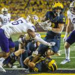 Michigan running back Blake Corum (2) steps over tight end Erick All (83) and past Washington defensive back Cameron Williams (6) to score a touchdown in the fourth quarter of a game Saturday in Ann Arbor, Mich. (AP Photo/Tony Ding)