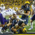 Michigan running back Blake Corum (2) steps over tight end Erick All (83) and past Washington defensive back Cameron Williams (6) to score a touchdown in the fourth quarter of an NCAA college football game in Ann Arbor, Mich., Saturday, Sept. 11, 2021. (AP Photo/Tony Ding)