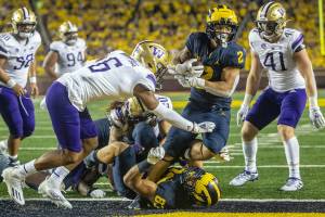 Michigan running back Blake Corum (2) steps over tight end Erick All (83) and past Washington defensive back Cameron Williams (6) to score a touchdown in the fourth quarter of an NCAA college football game in Ann Arbor, Mich., Saturday, Sept. 11, 2021. (AP Photo/Tony Ding)