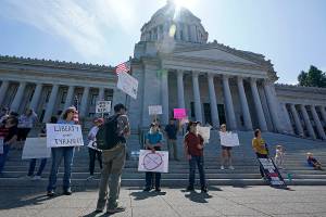 Protesters who oppose mask and COVID-19 vaccine mandates gather outside the Legislative Building, Wednesday, Aug. 18, 2021, at the Capitol in Olympia, Wash. Washington Gov. Jay Inslee announced Wednesday that Washington state is expanding its vaccine mandate to include all public, charter and private school teachers and staff, as well as those working at the state's colleges and universities. Inslee also expanded the statewide indoor mask mandate in place for non-vaccinated individuals to include those who are vaccinated. (AP Photo/Ted S. Warren)
