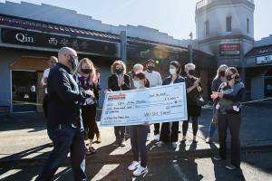 Bufeng Gao, owner of Qin Xi'an Noodles, receives a check from the Edmonds Chamber Foundation's Wish Fund outside of her restaurant that was burned in a fire on Thursday, Sept. 16, 2021 in Edmonds, Wa. (Olivia Vanni / The Herald)