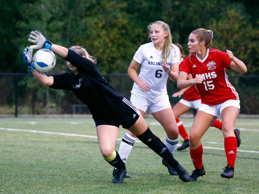 Arlingtons Allexine Miller-Wood blocks a shot with teammate Arlingtons Madyson Williams and Archbishop Murphys Jordyn Latta looking on at Archbishop Murphy High School Tuesday night in Everett on September 14, 2021. The Wildcats won 6-1. (Kevin Clark / The Herald)