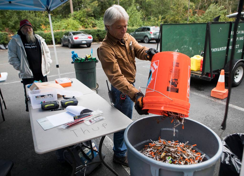 Tony Thompson, operations coordinator with The Hand Up Project, dumps collected needles into a trash bin Sunday near Everett. (Olivia Vanni / The Herald)