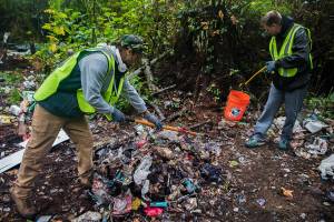 David Rice-Whichers, right, and Justin Dull, volunteers with the Hands Up Project, search for needles during a clean up of an encampment along 130th Street on Sunday, Sept. 19, 2021 in Everett, Wa. (Olivia Vanni / The Herald)