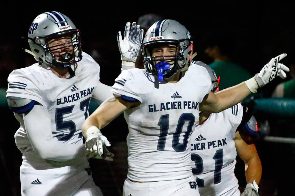 Glacier Peaks Konner Meyer, left, celebrates Ryan Kings interception and return for a touchdown Thursday evening at Pop Keeney Stadium in Bothell on September 16, 2021. (Kevin Clark / The Herald)
